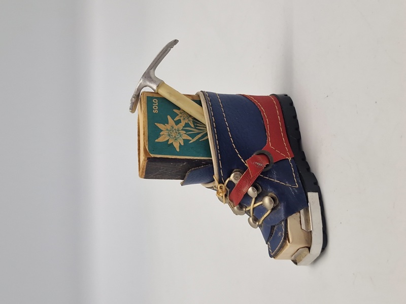 miniature af en skistøvle, der fungerer som en holder til en æske tændstikker og en lille ishakke.