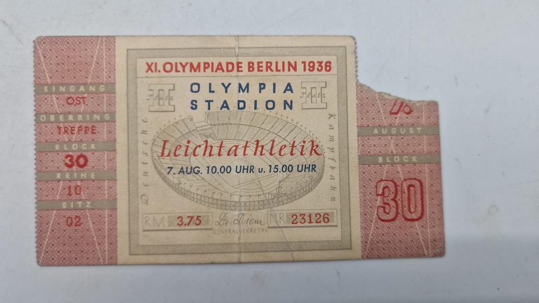 Original billet til De XI Olympiske Lege i Berlin i 1936. 
Billetten er til atletikbegivenheder i Olympiastadion den 7. august, kl. 10.00 og 15.00. 