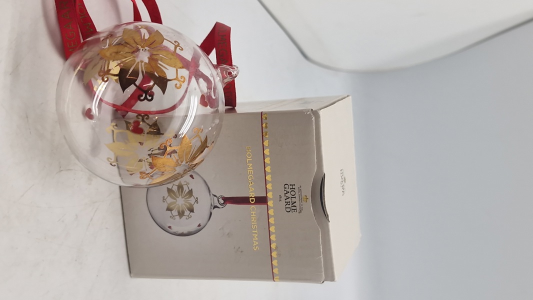 Holmegaard Christmas årets julekugle 2024, designet i klart glas med guld- og røde detaljer