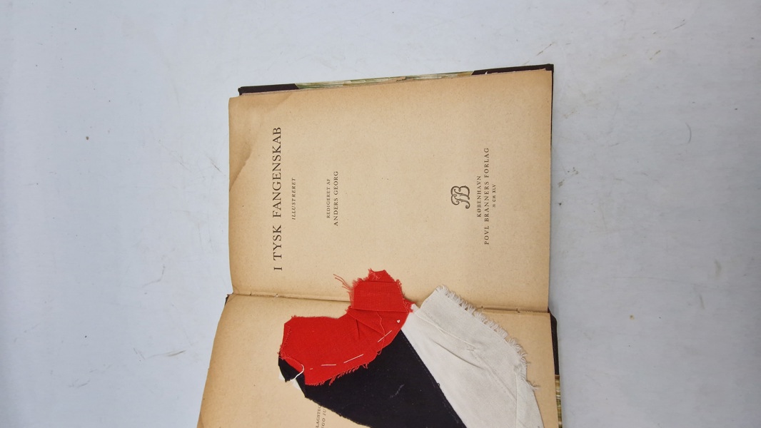 Bog fra dansk krigsfange med stump af tysk hagekors flag. Originalt